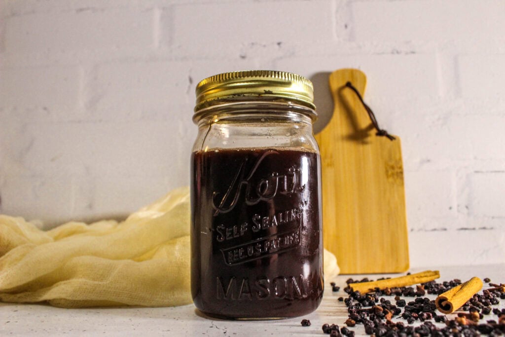 Homemade elderberry syrup in a glass mason jar.