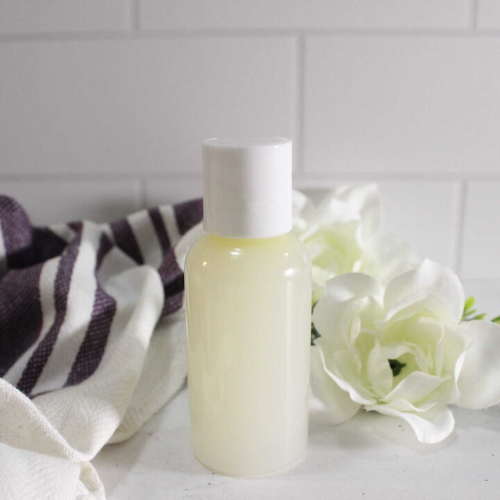 Herbal micellar water in a bottle, styled with a white flower and a cloth in the background.