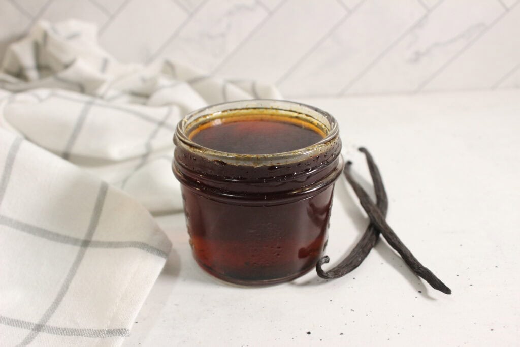 Homemade vanilla extract in a glass jar with vanilla beans.