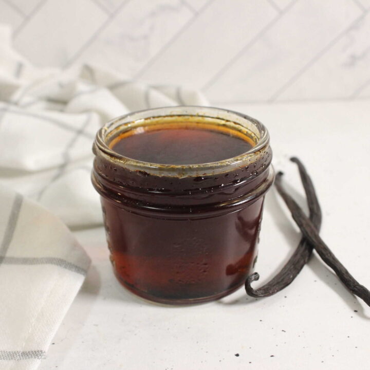 Homemade vanilla extract in a glass jar with vanilla beans.