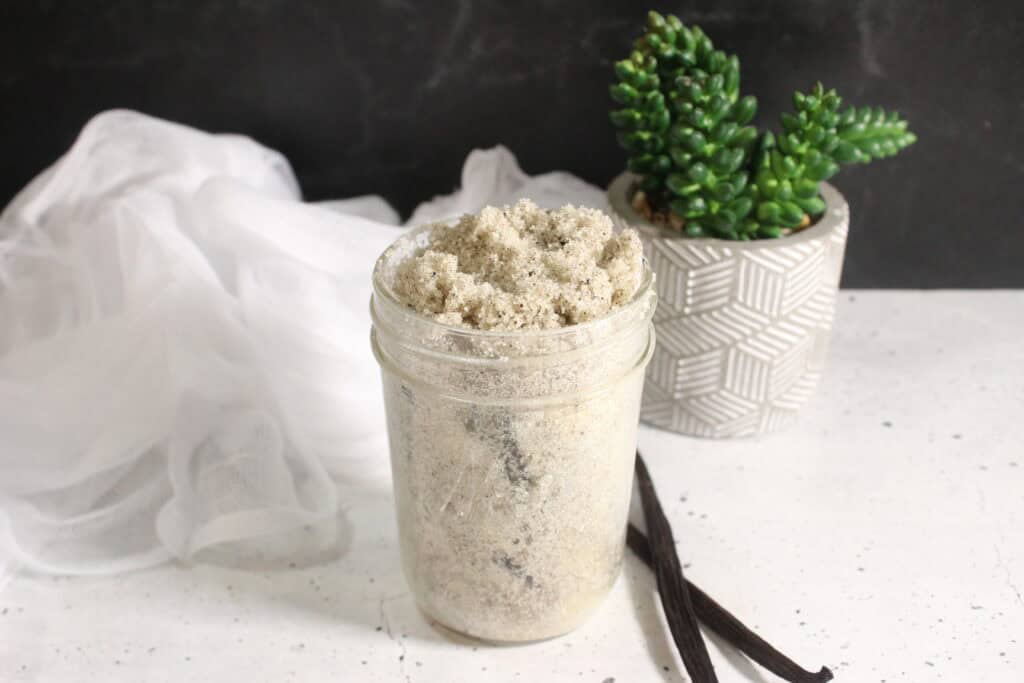 Jar of vanilla sugar with a whole vanilla bean inside and vanilla pods beside it.