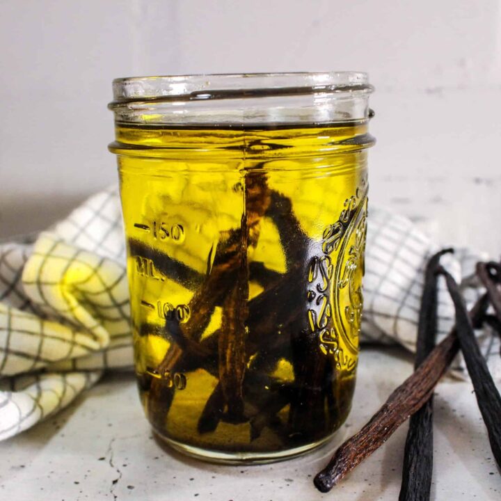 Glass jar of vanilla oil infusion, beans fully submerged.