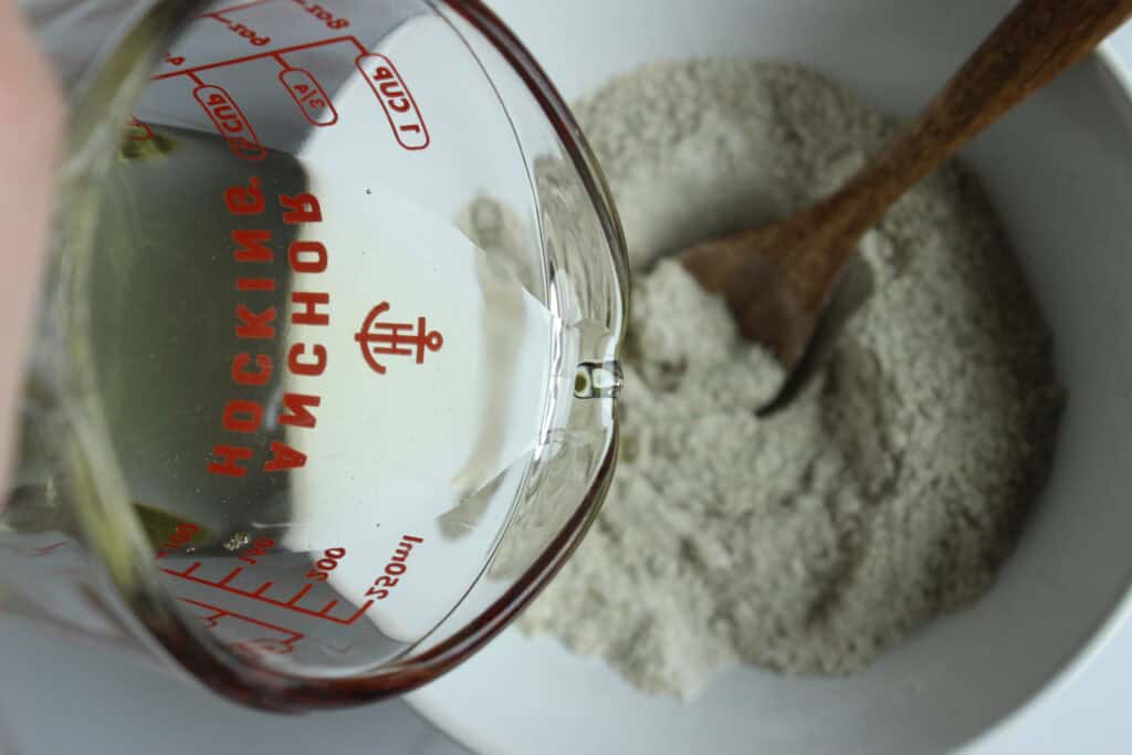 Pouring liquid tallow into a bowl of powdered ingredients