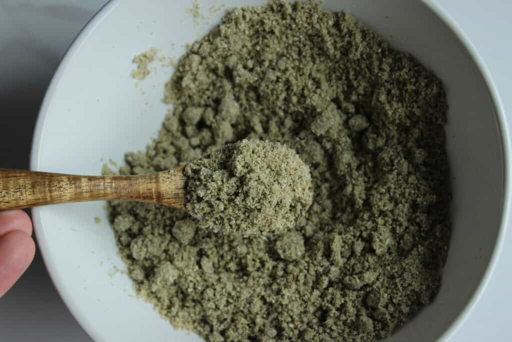a jar of homemade lavender tallow oatmeal face scrub, showcasing its natural, textured appearance alongside a bowl of creamy lotion and dried lavender.