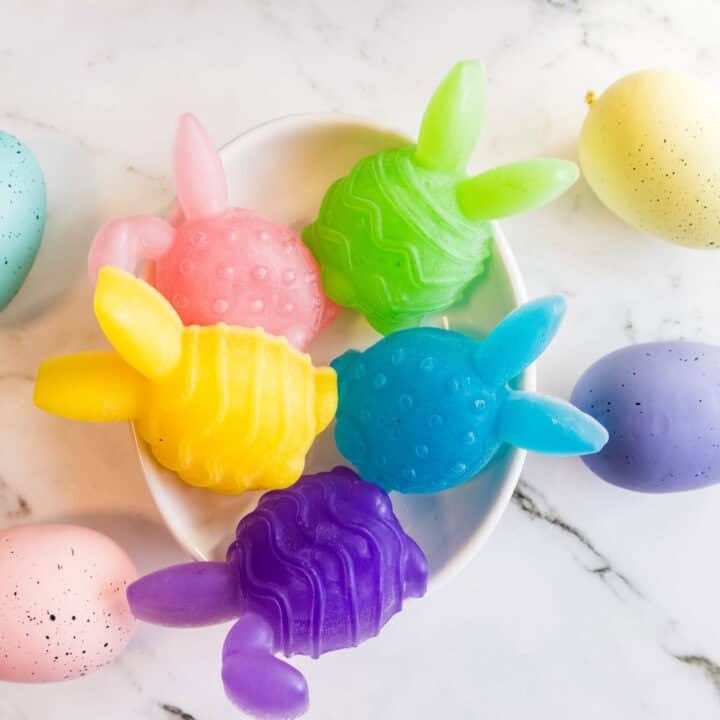 Colorful Easter bunny-shaped soaps with pastel eggs on marble background.