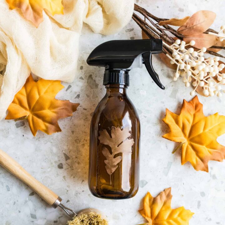 Amber trigger spray bottle with cinnamon sticks, dried flowers, and autumn leaves