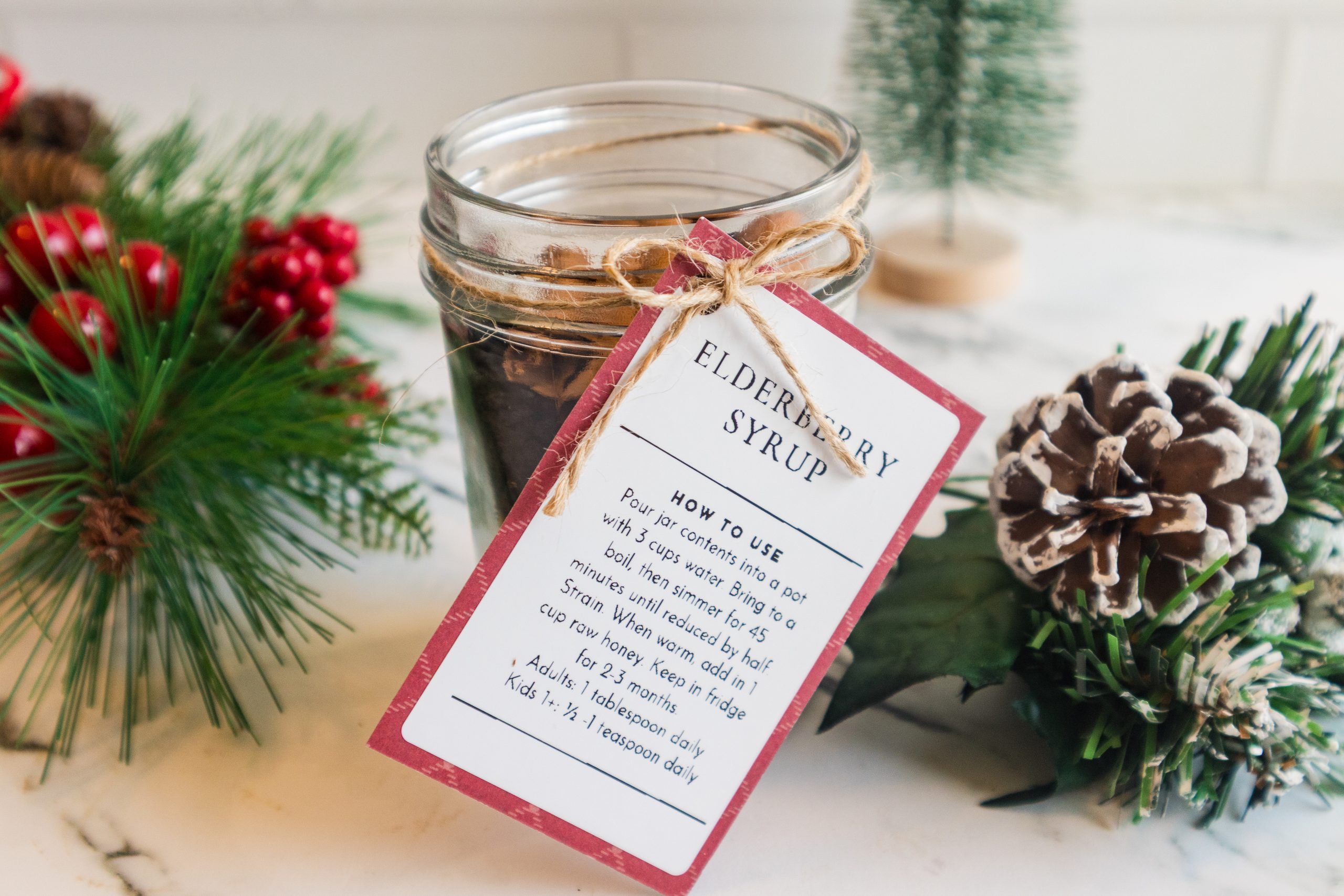 Cinnamon sticks in a glass jar with a holiday gift tag and pinecones.